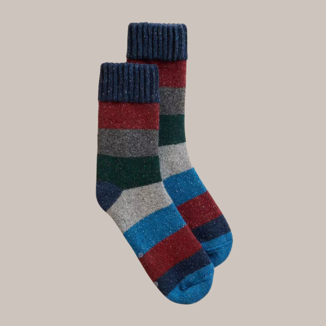 Pair of multicolored striped wool socks. Features navy blue cuffs and horizontal stripes in red, grey, dark green, and blue.