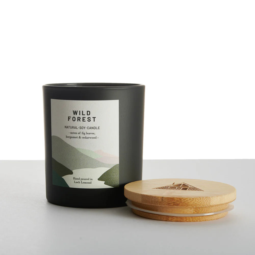 Black matte Wild Forest natural soy candle with a minimalist label featuring fig leaves, bergamot, and cedarwood notes.