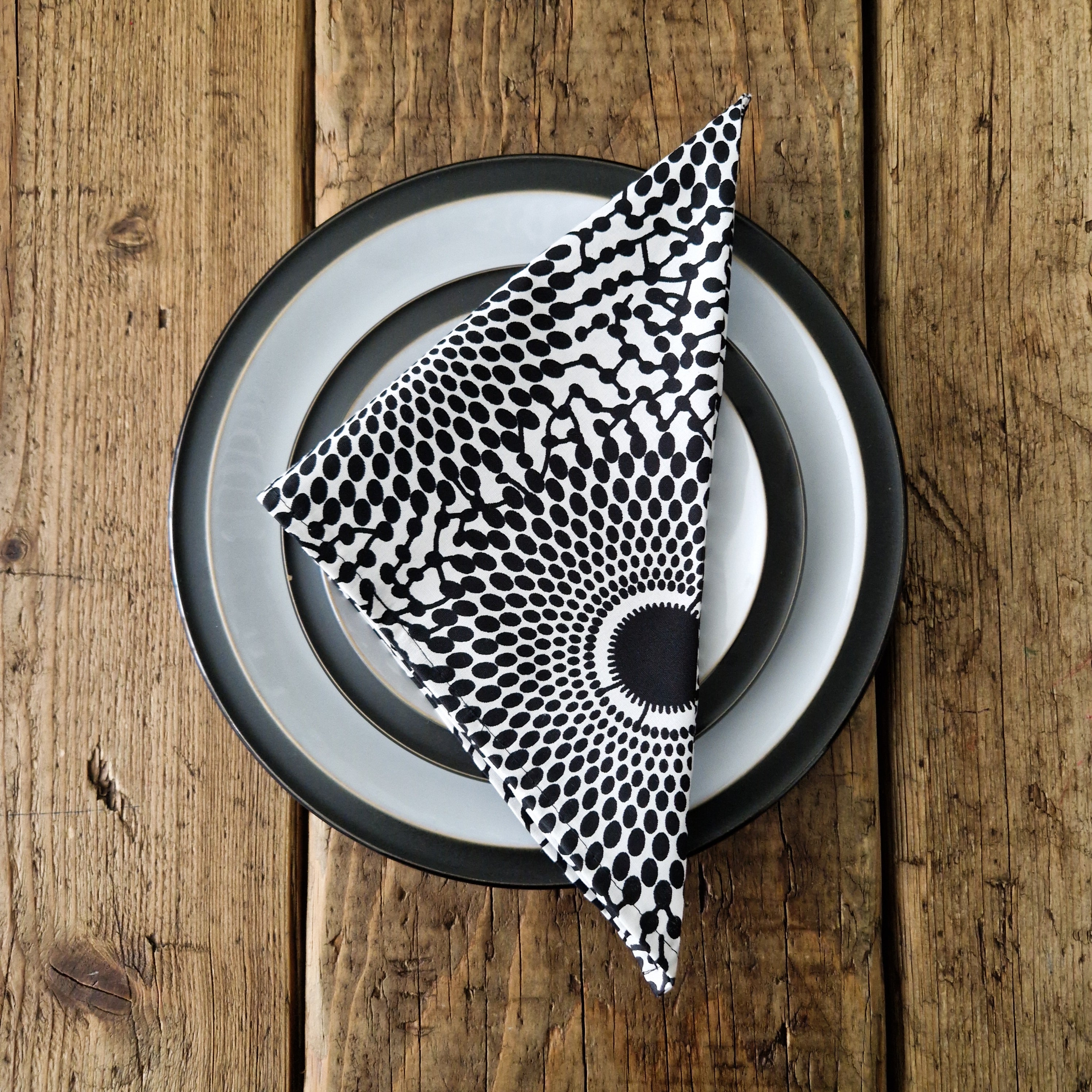 Black and white patterned cloth napkin folded on a dark gray and white plate.