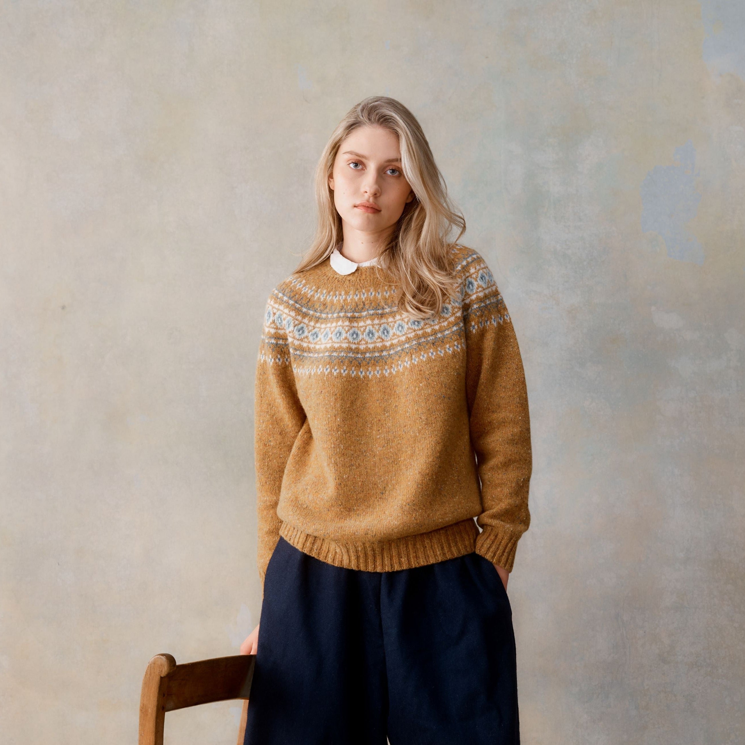 Mustard-colored wool sweater with a Fair Isle-style yoke featuring blue and white patterns.