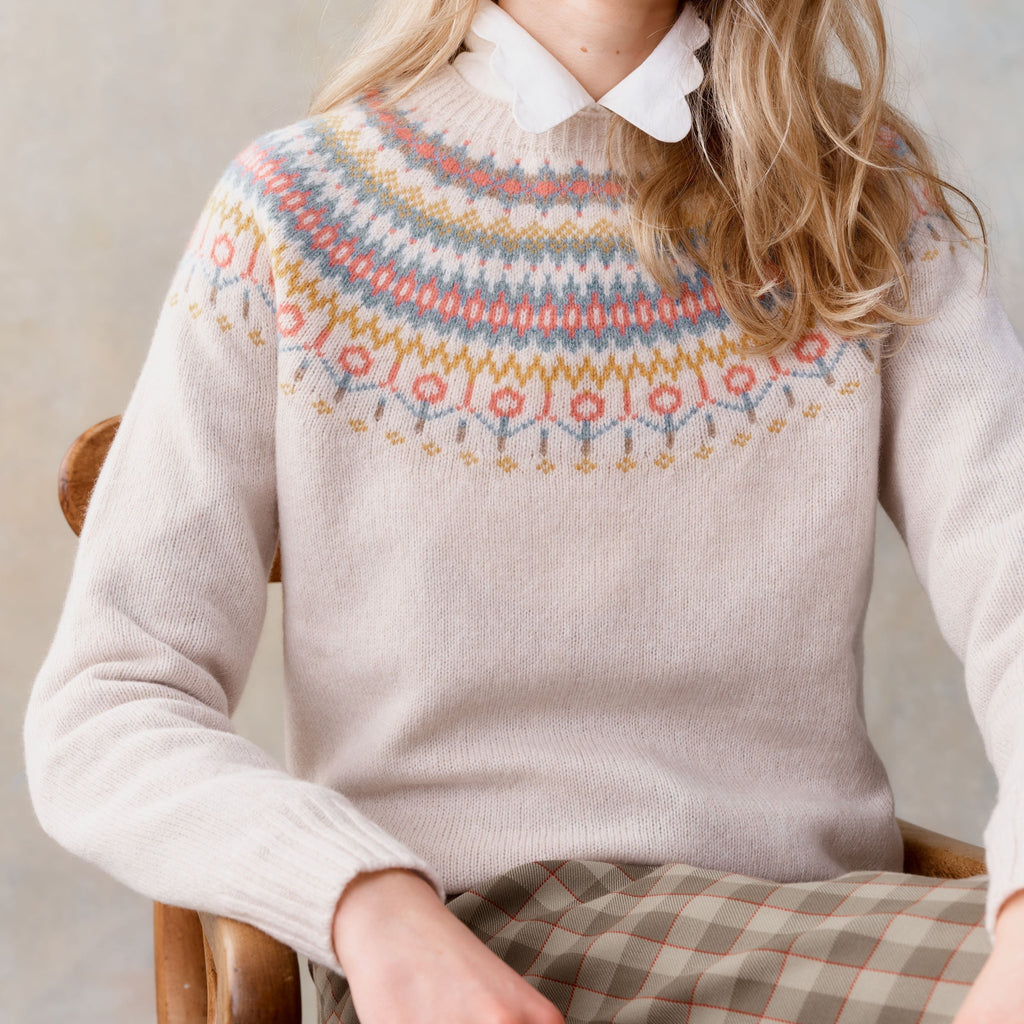 Cream-colored knit sweater with a Fair Isle-style yoke featuring muted pastel colors and geometric patterns.