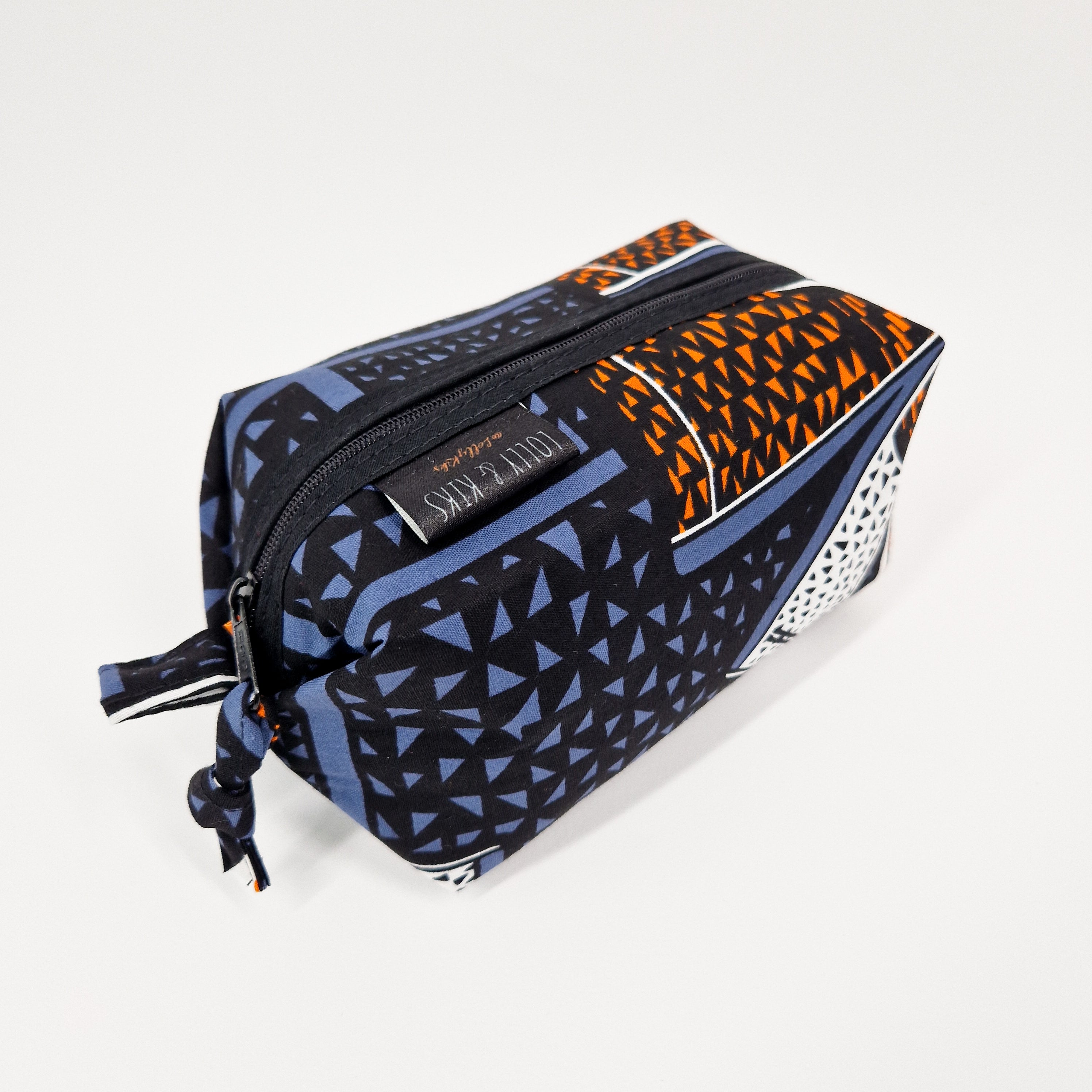 Rectangular zippered pouch with a geometric print in shades of blue, black, and orange.  The fabric appears to be cotton.