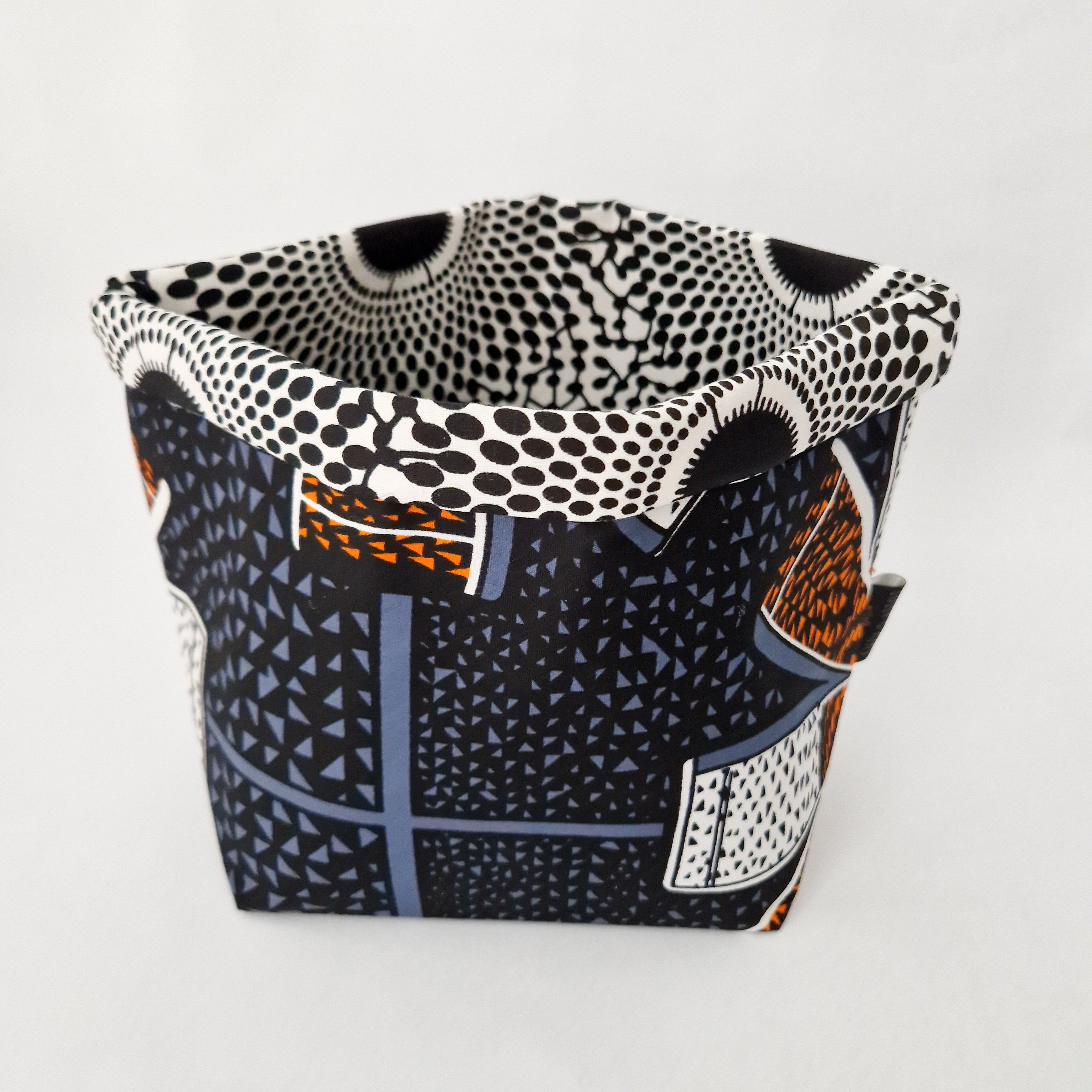 Small fabric storage container with a black, white, gray, and orange geometric and polka dot pattern.