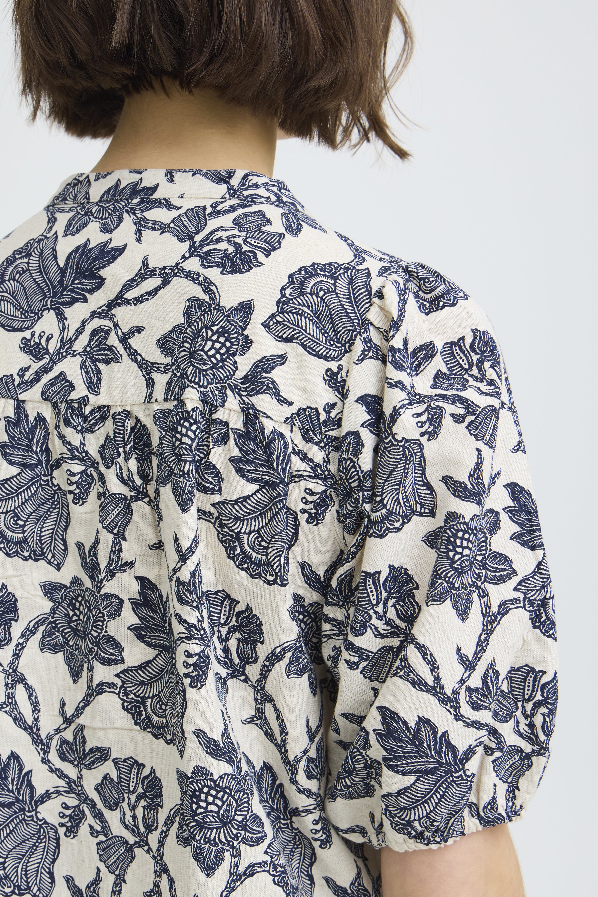 Person wearing a floral patterned shirt with a plain background