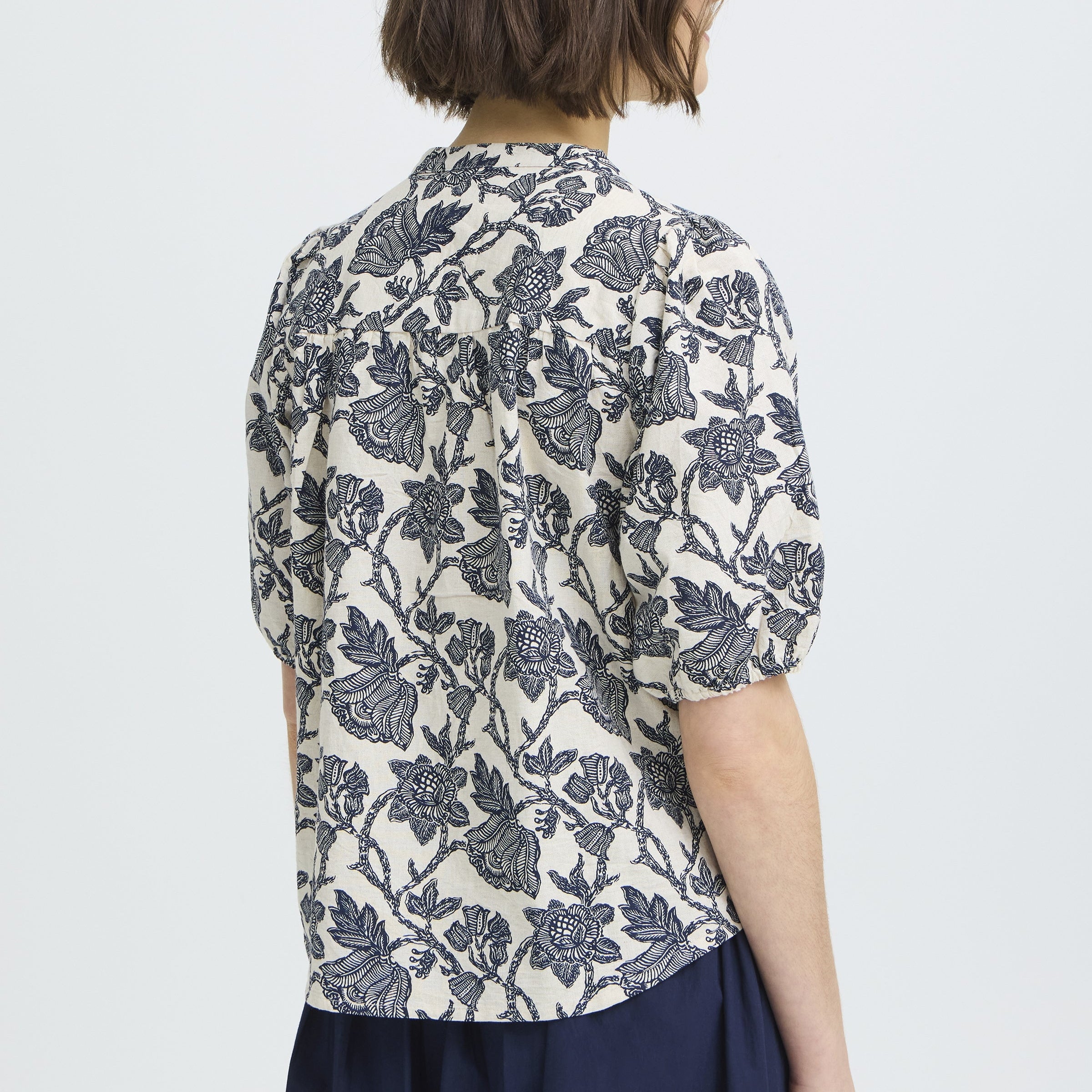 Person wearing a floral patterned shirt on a plain background