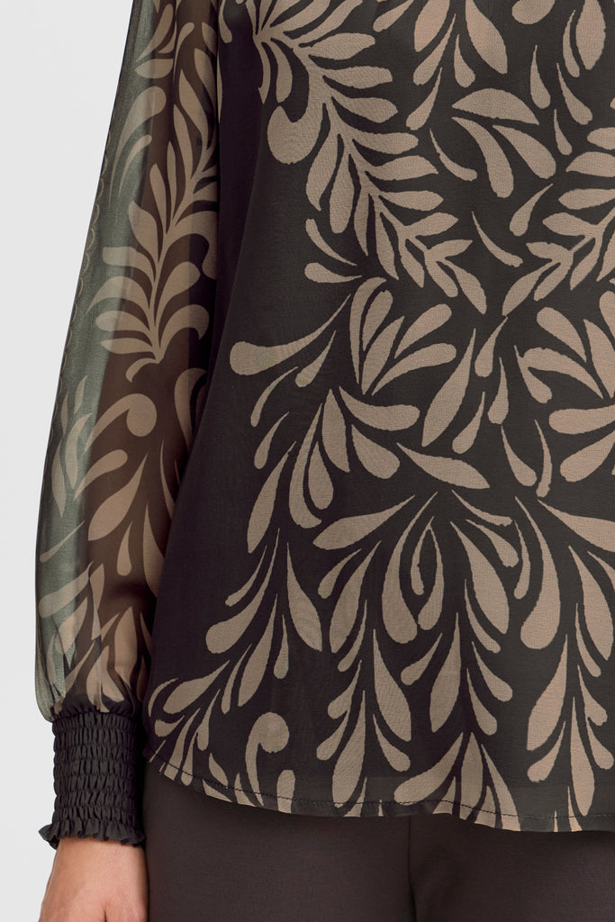 Close-up of a Fransa blouse featuring a black fabric with beige leaf patterns and smocked black cuffs.