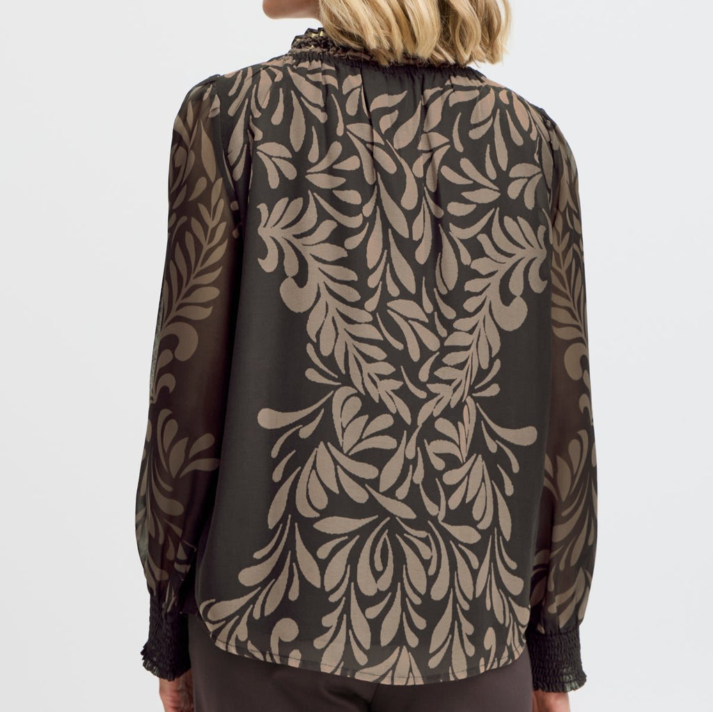 Back view of a woman wearing a Fransa blouse with a black base and beige leaf pattern.