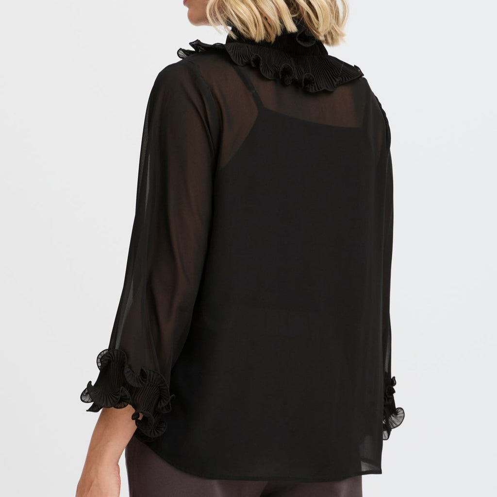 Black sheer blouse with ruffled collar and cuffs by Fransa, styled from the back.