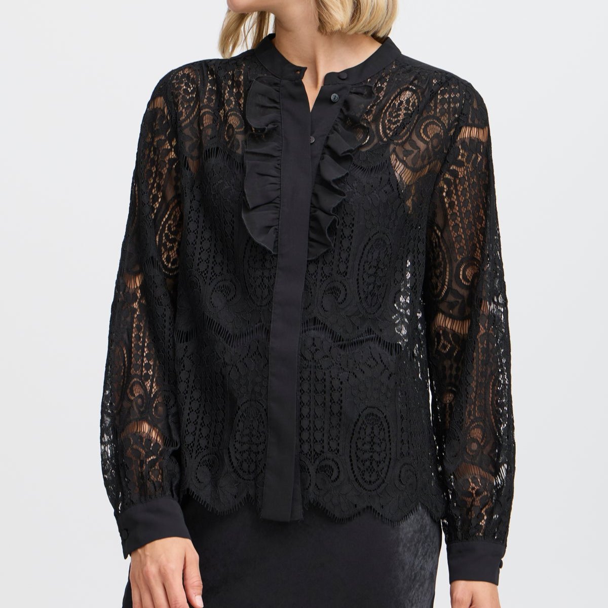 Black lace blouse with ruffled neckline and long sleeves.  The intricate lace pattern covers a solid black underlayer.