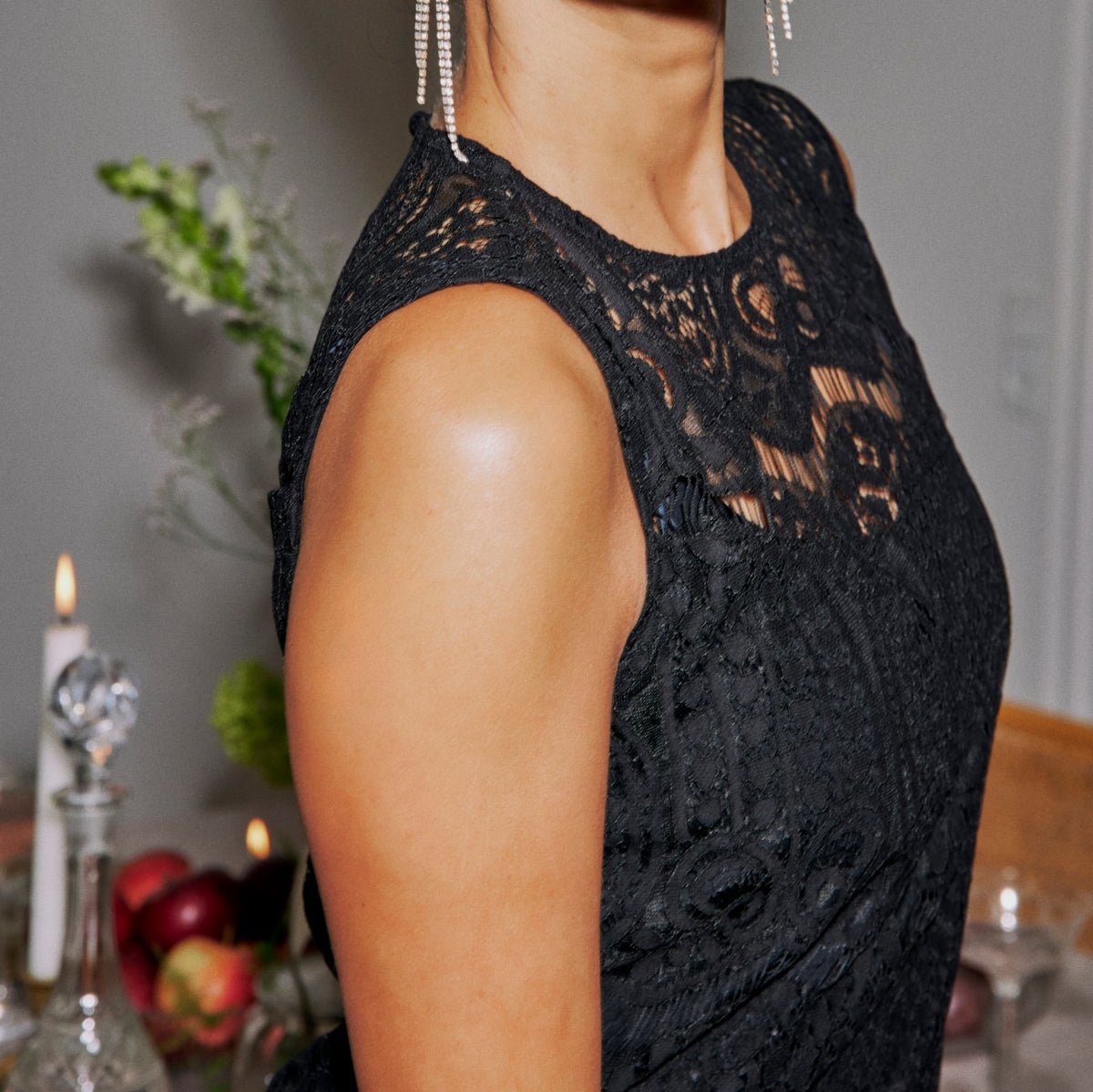 Black sleeveless lace dress with a high neckline.