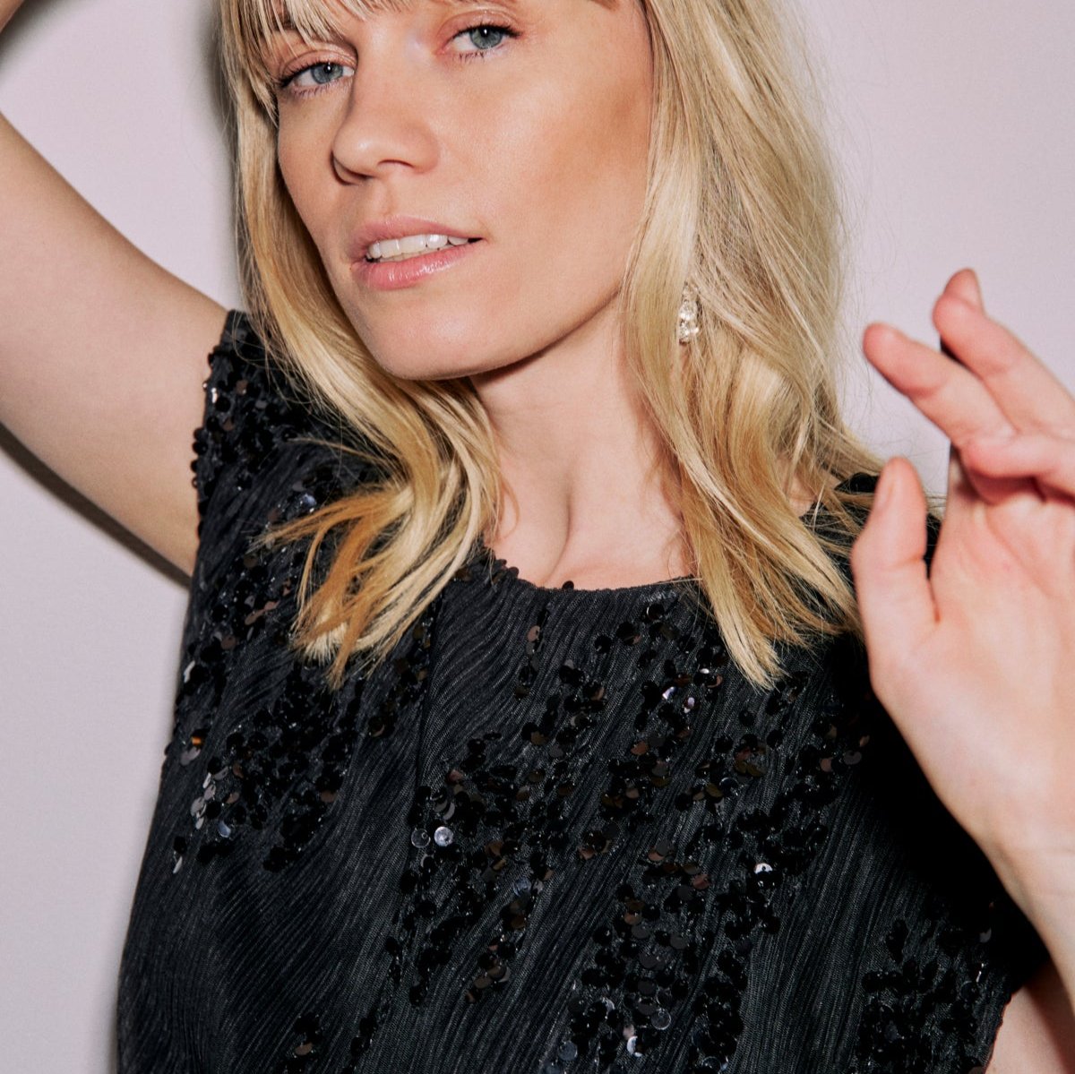 Black sequined mini dress with short sleeves and a round neckline.  The sequins are clustered in a patterned design.