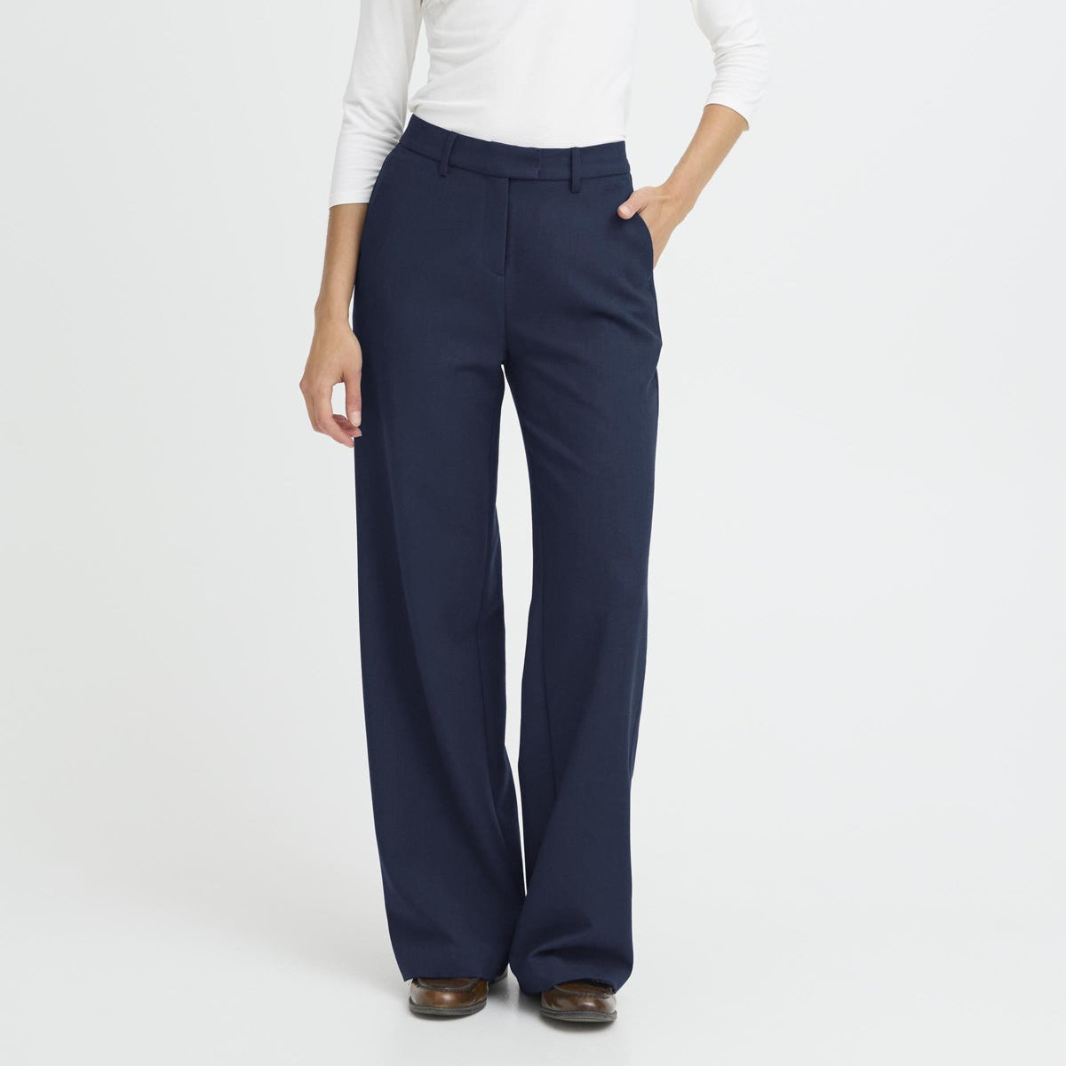 Woman wearing navy pants and a white top on a white background
