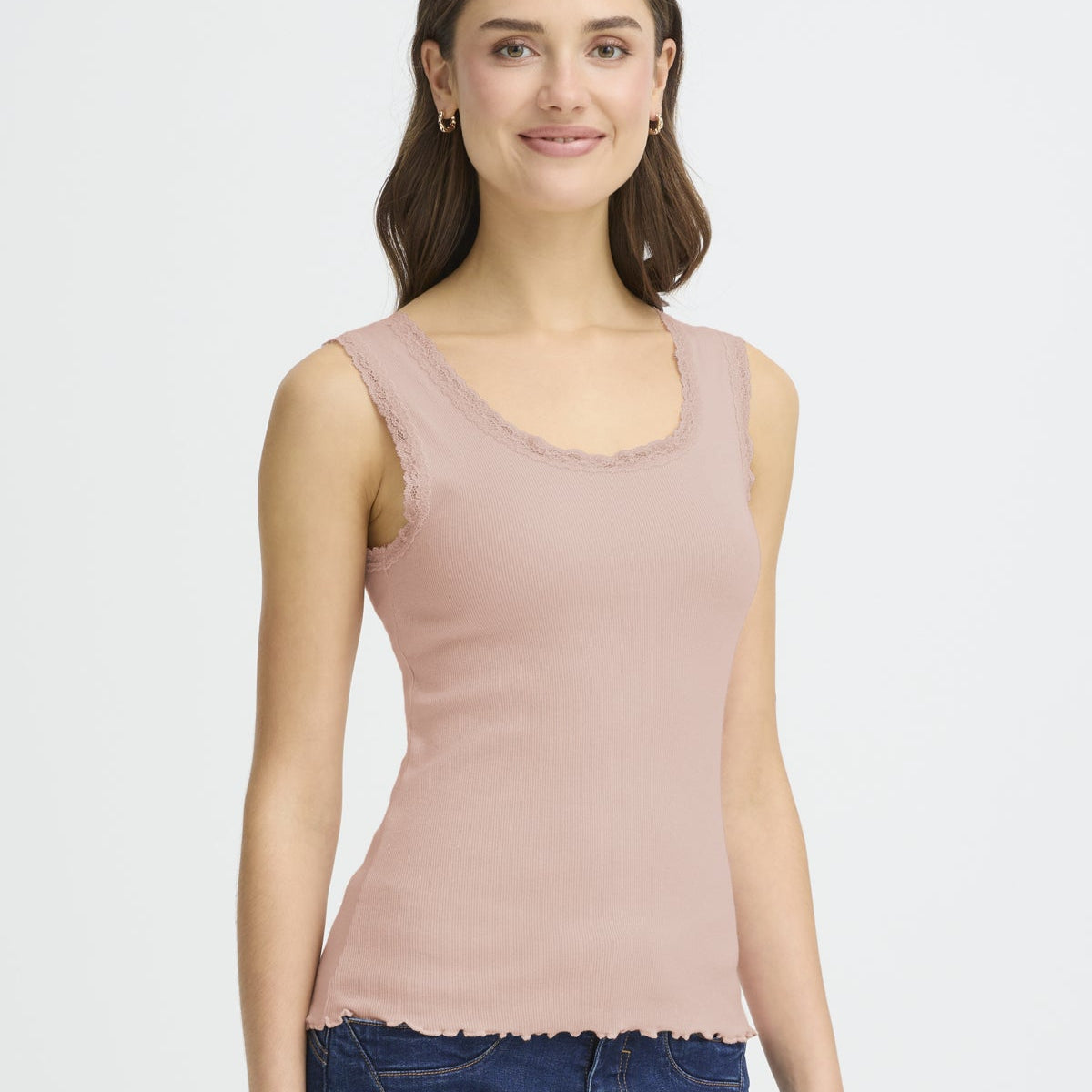 Woman wearing a light pink tank top against a white background