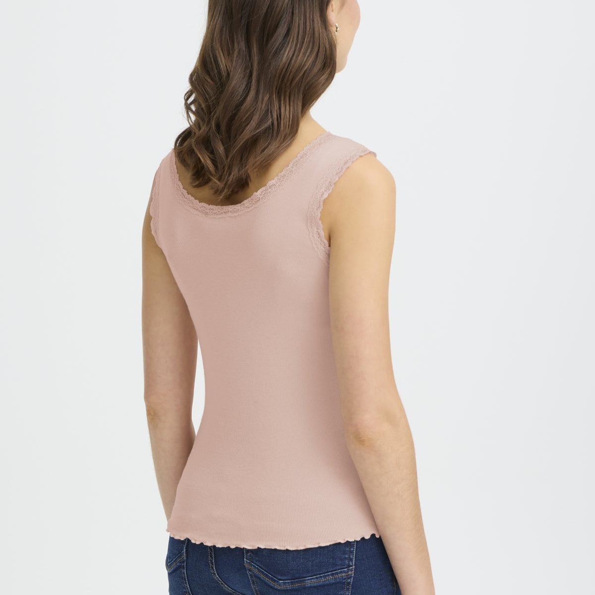 Woman wearing a light pink sleeveless top on a white background