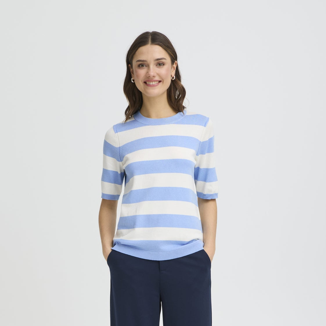 Woman wearing a blue and white striped sweater on a light gray background