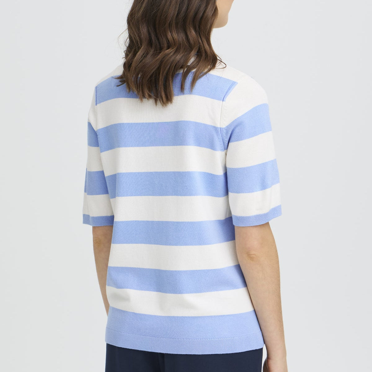 Woman wearing a blue and white striped shirt on a light gray background