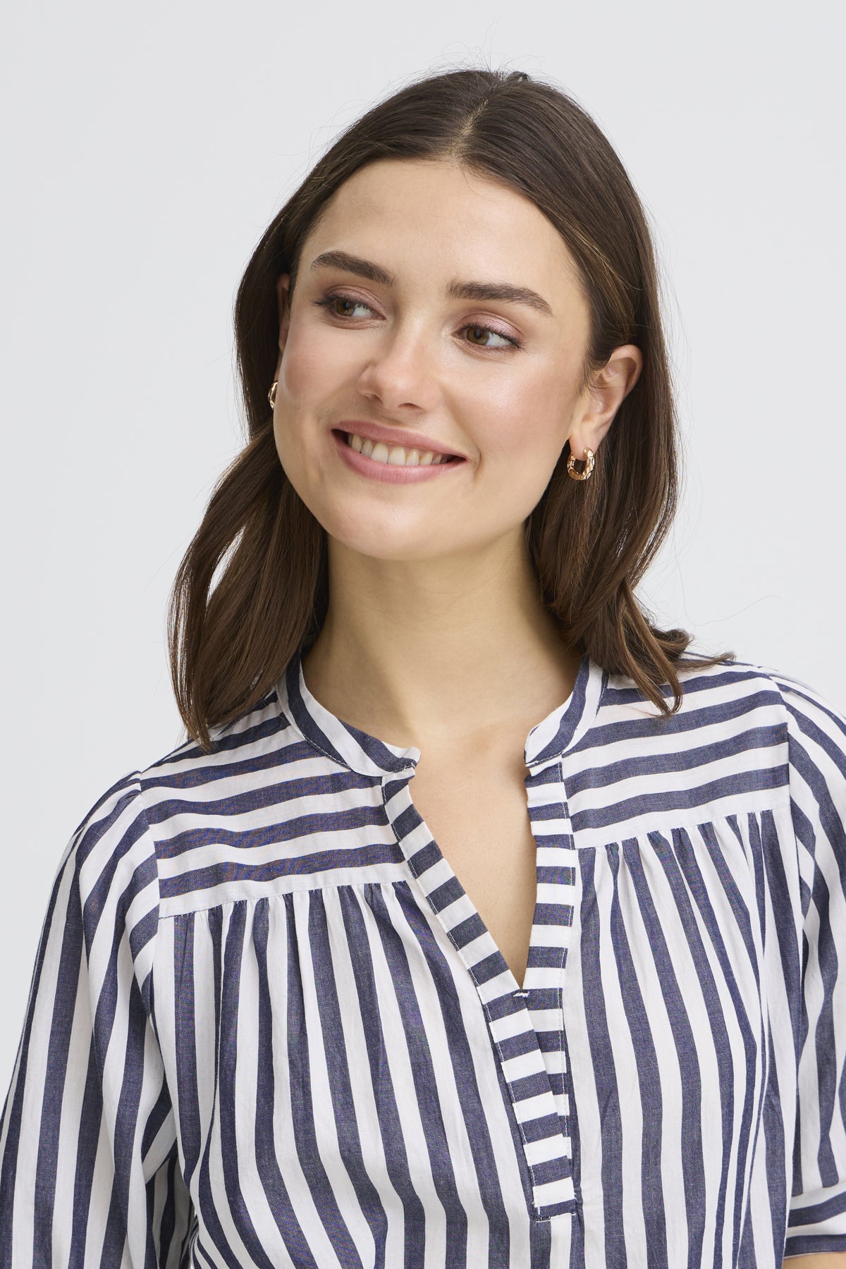 Woman wearing a blue and white striped shirt against a plain background
