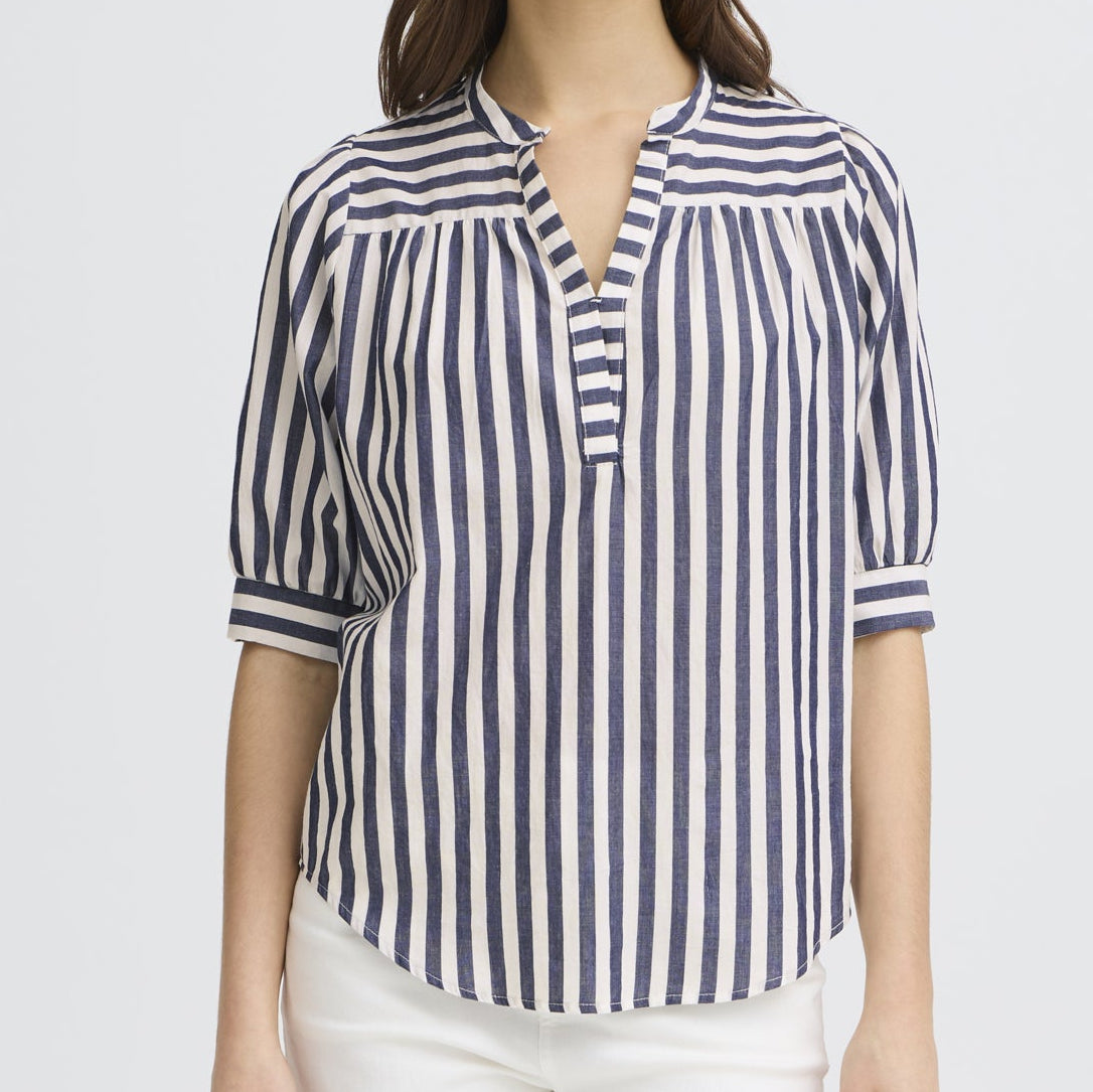 Woman wearing a navy and white striped shirt on a light gray background
