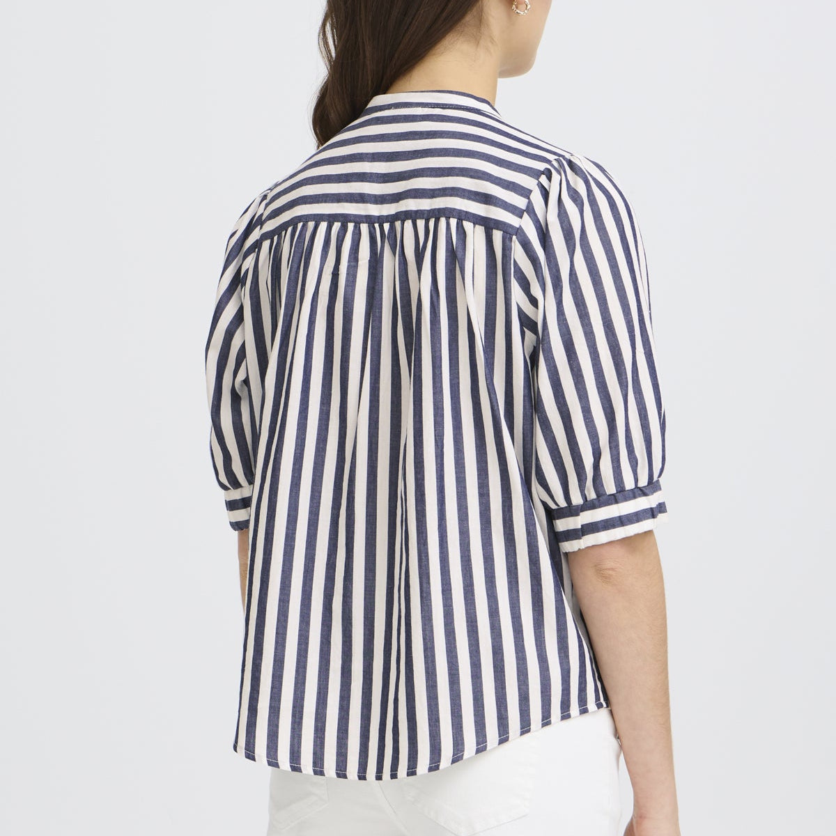Woman wearing a blue and white striped shirt on a light gray background