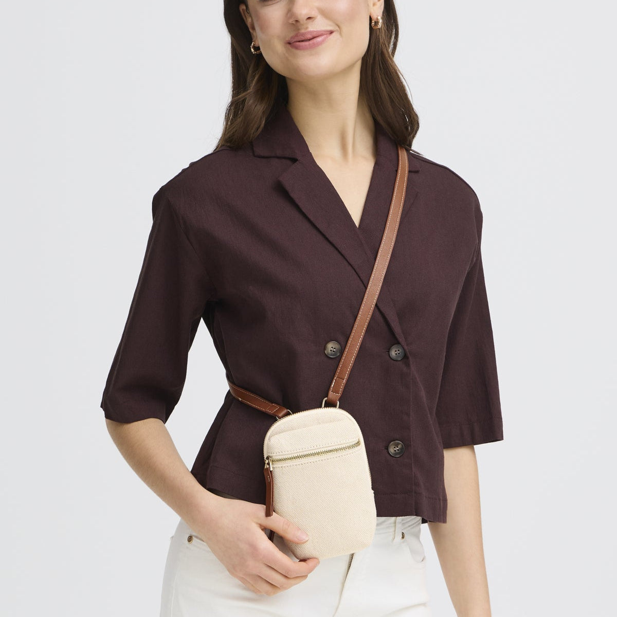 Woman wearing a brown blazer with a beige handbag on a white background