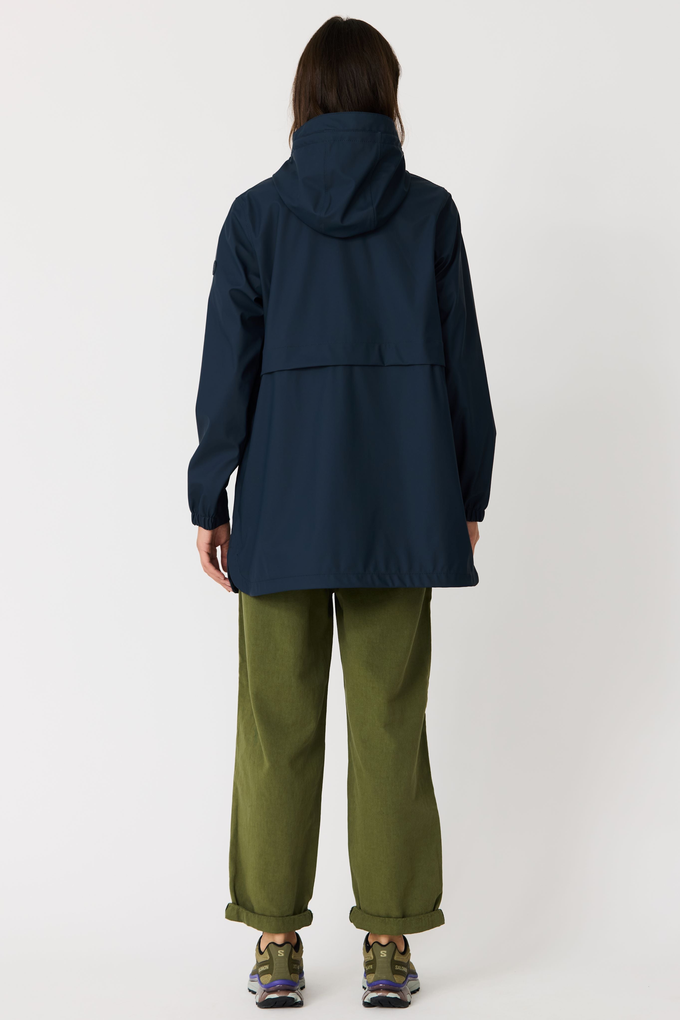 Person wearing a dark blue jacket and green pants on a white background