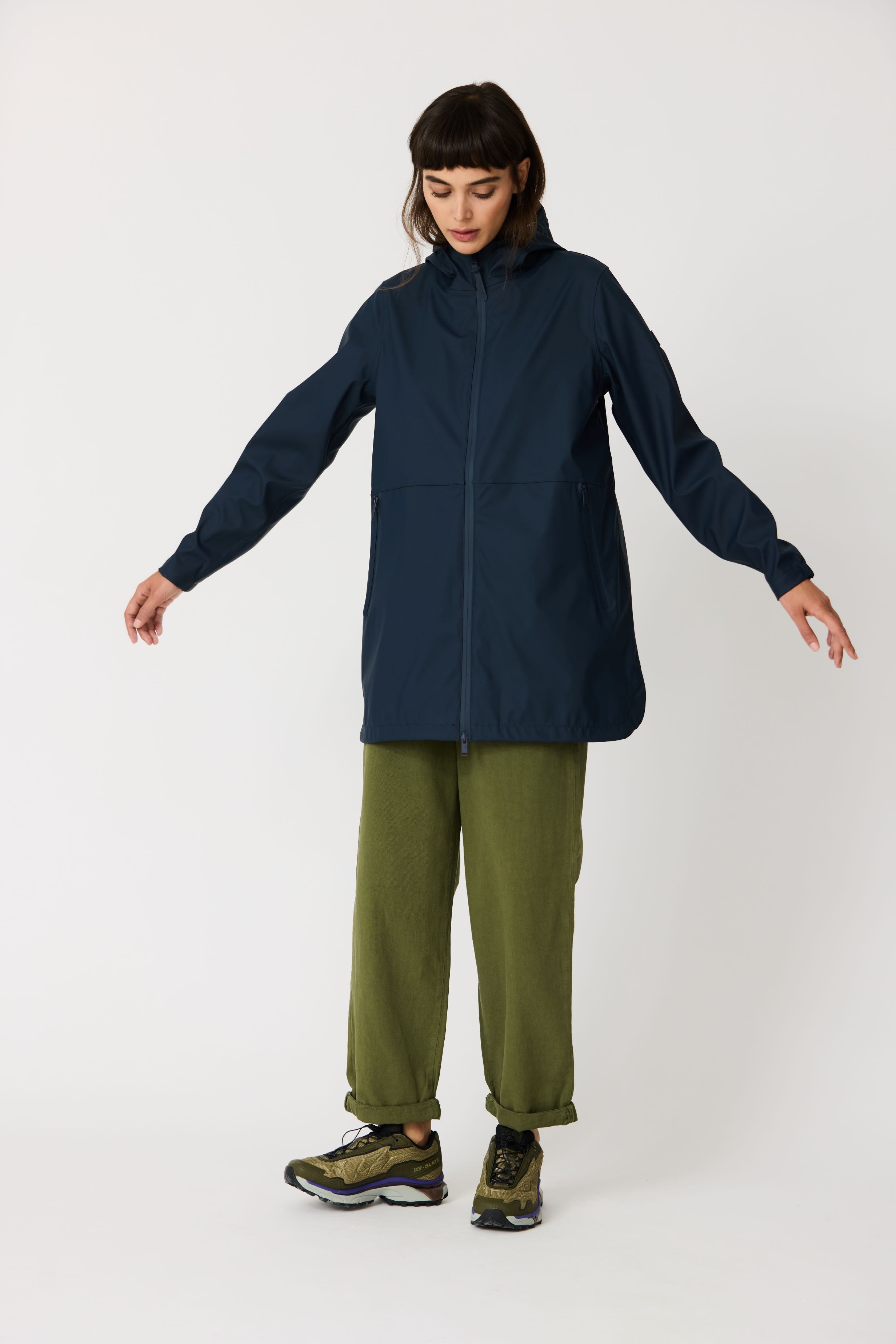 Person wearing a navy coat and green pants on a white background