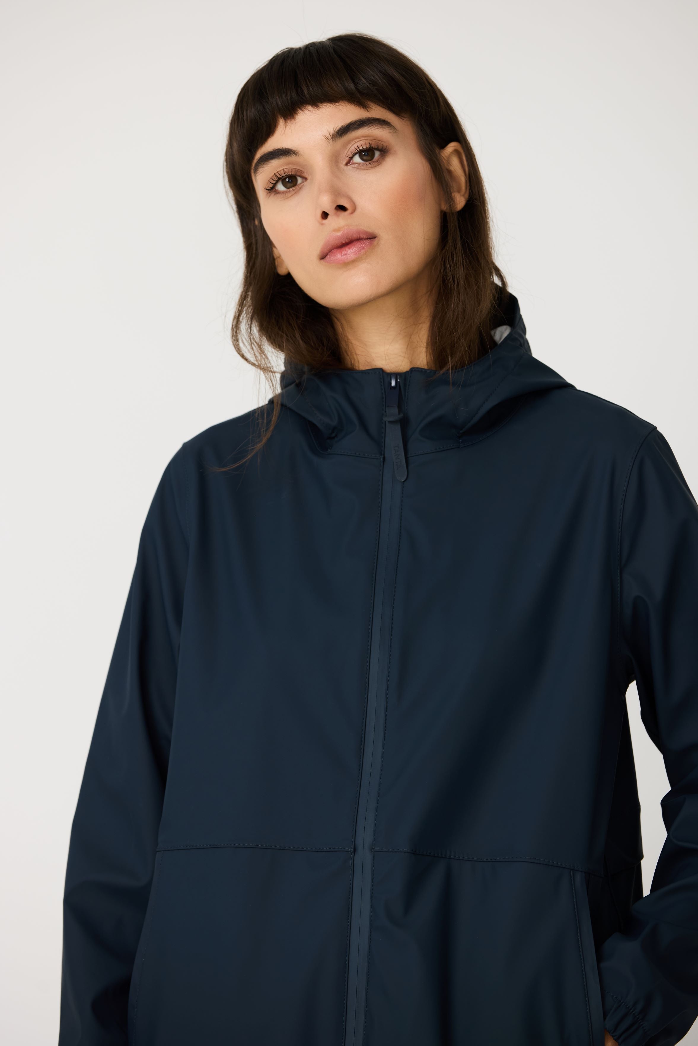 Woman wearing a navy blue raincoat against a white background