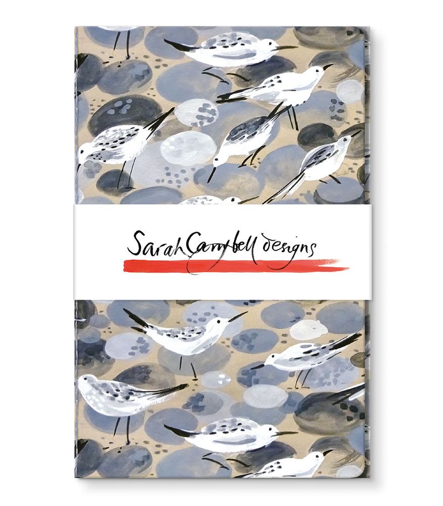 Notebook with stylized illustration of sandpipers on a pebble background. Sarah Campbell Designs logo visible on cover band.