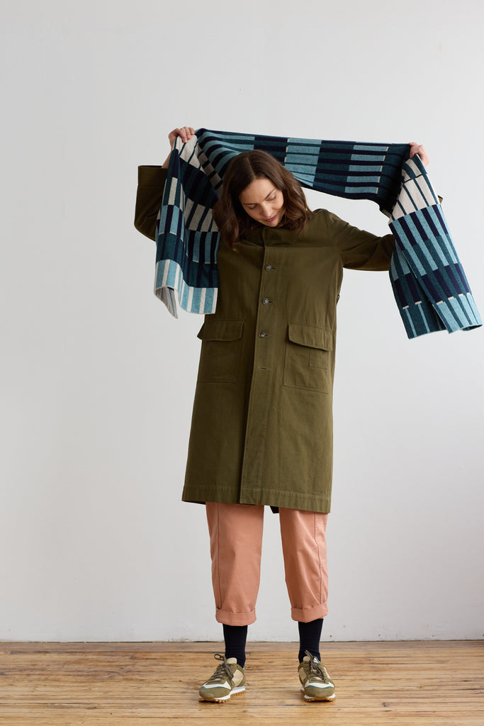 A teal and cream striped wool throw blanket draped over a person's shoulders.