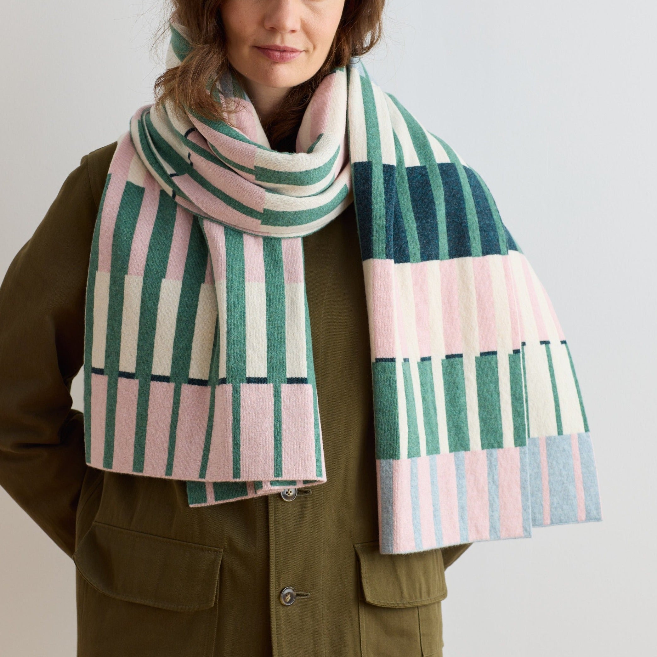 Striped wool scarf in shades of pink, green, and cream.  The design features vertical stripes arranged in blocks of color.