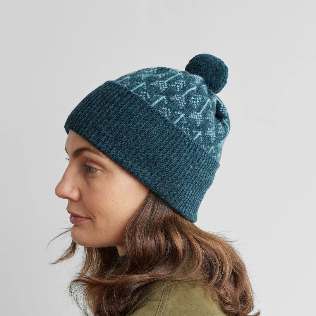 Teal knit beanie with a pom-pom and a light teal Fair Isle pattern.