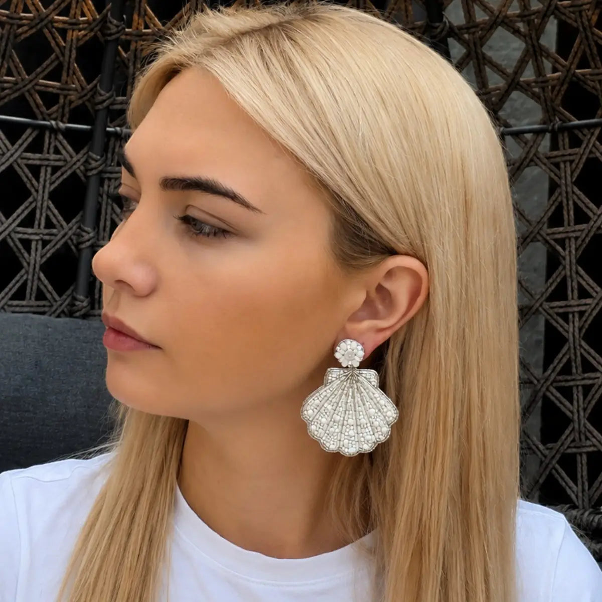 Woman wearing a shell-shaped earring with a decorative background