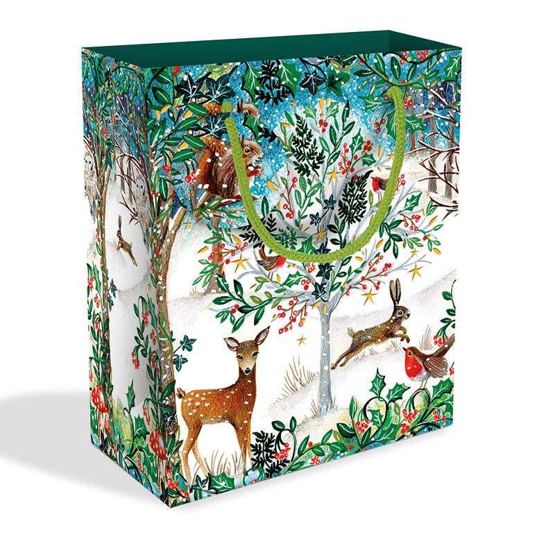 A decorative gift bag with a winter woodland illustration featuring deer, a rabbit, birds, and trees in green, red, blue, and white, with dark green handles and a dark green top opening, shown on a white background.