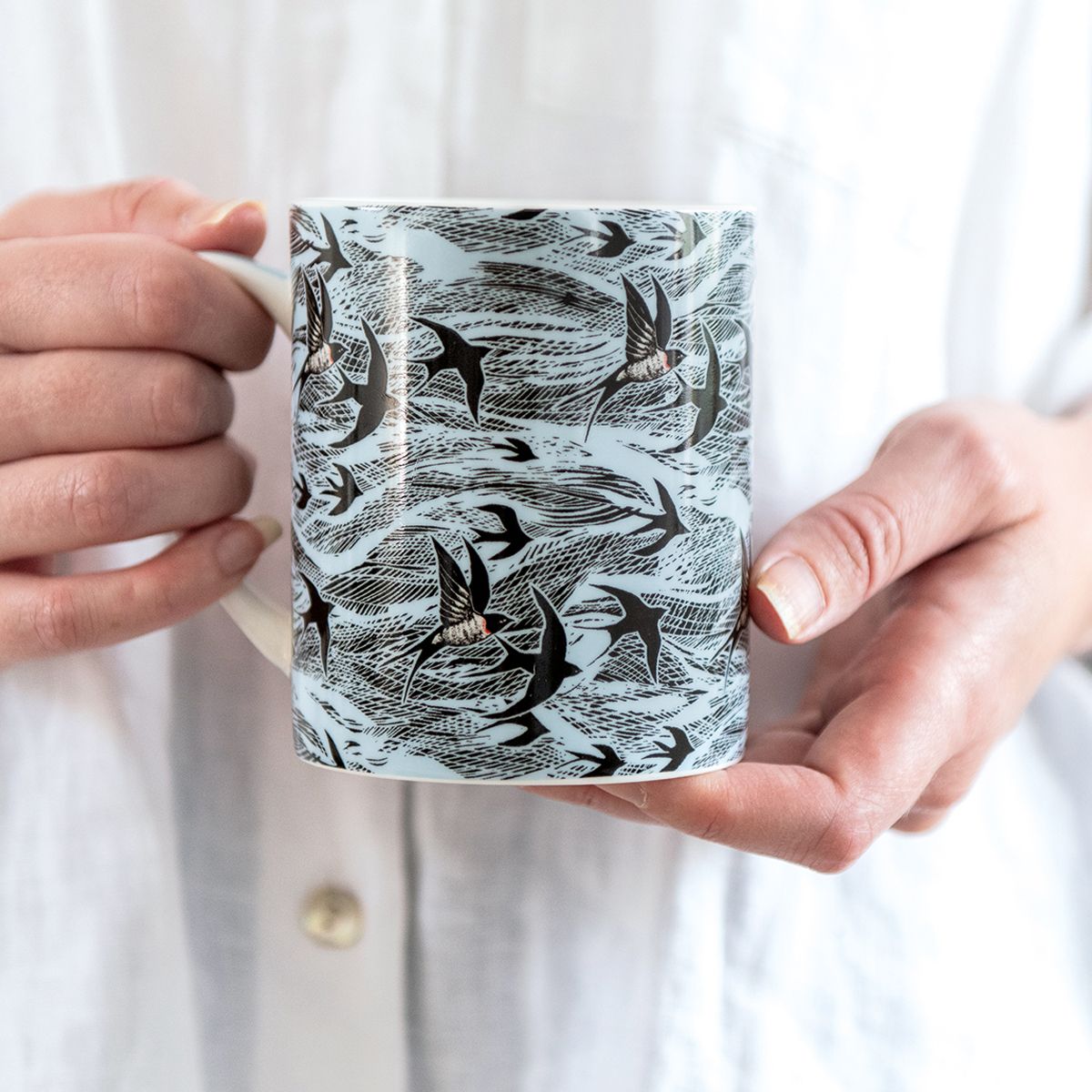 Person holding a mug with bird pattern design