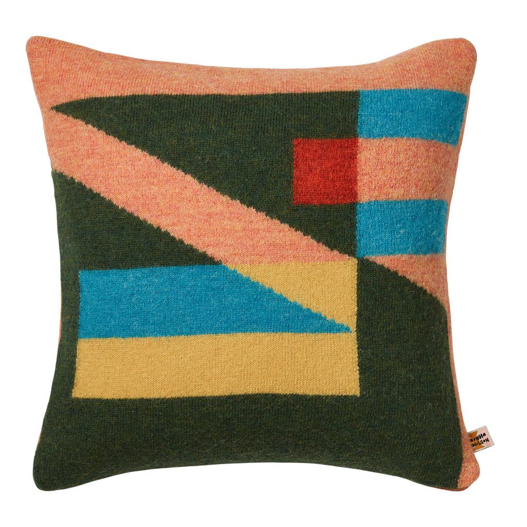 Colorful geometric cushion by Donna Wilson, featuring green, pink, blue, yellow, and red patterns.