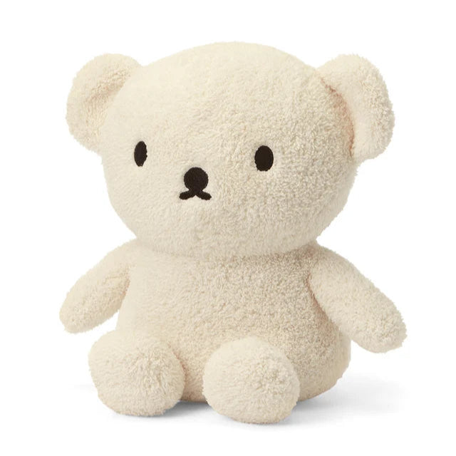 Cream-colored plush teddy bear with simple black facial features.  Soft, textured fur.