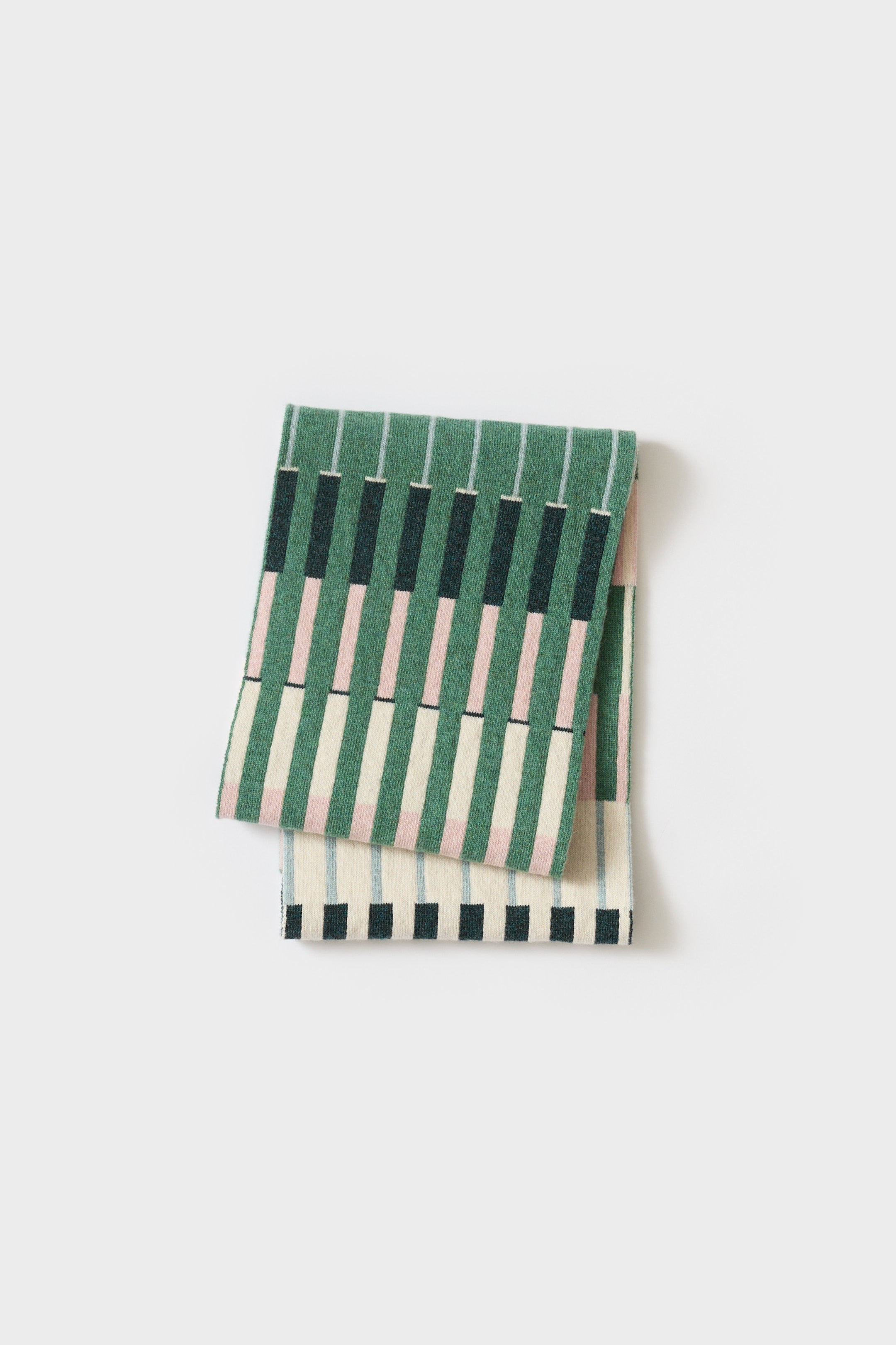 Folded green and cream striped knit scarf with a geometric pattern.  The scarf features darker green and pink accents.