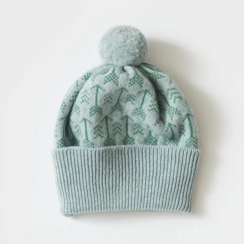 Light teal knitted beanie with a pompom and a repeating pattern of small green trees.