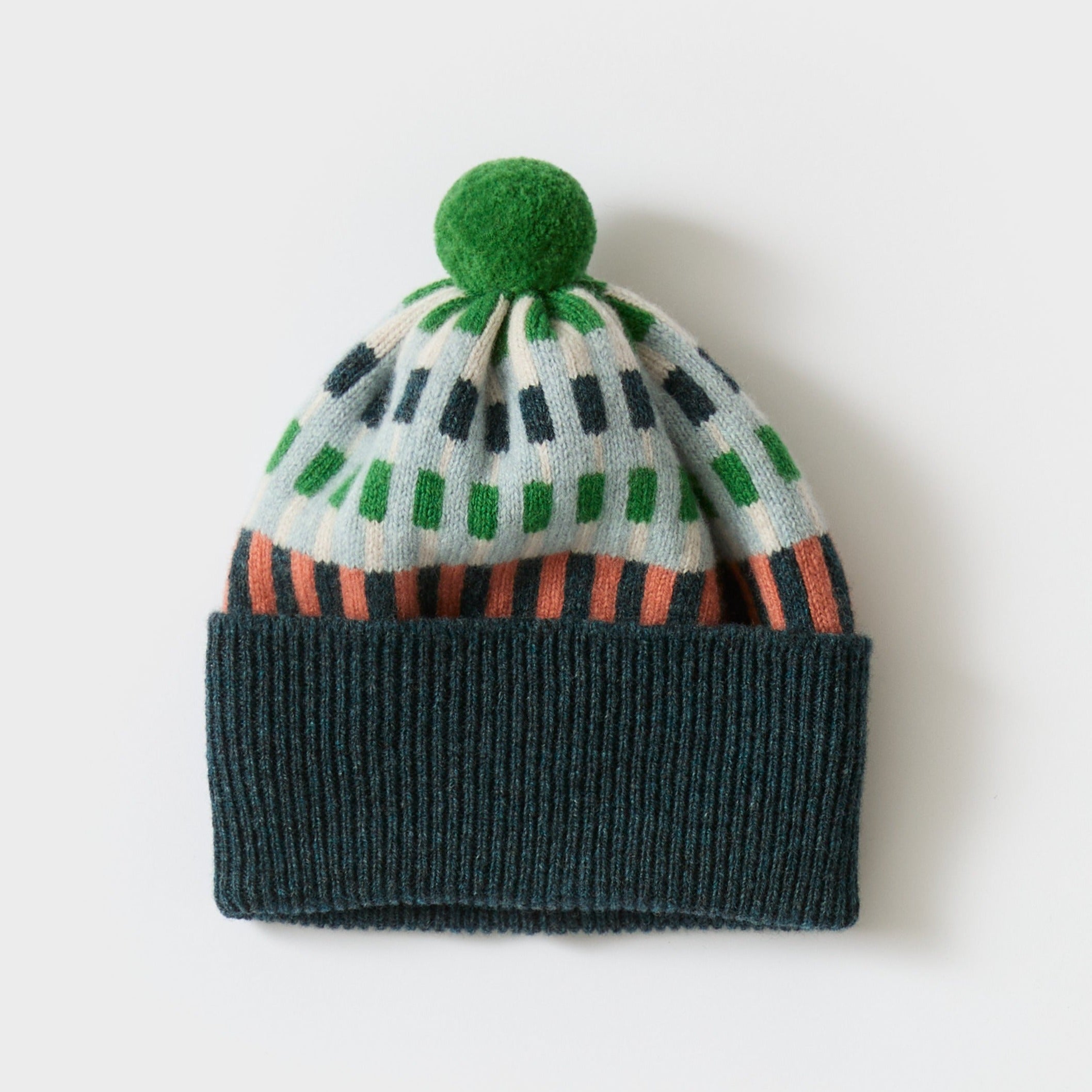 Green pom-pom beanie with teal ribbed cuff and a light blue, green, and coral geometric pattern.