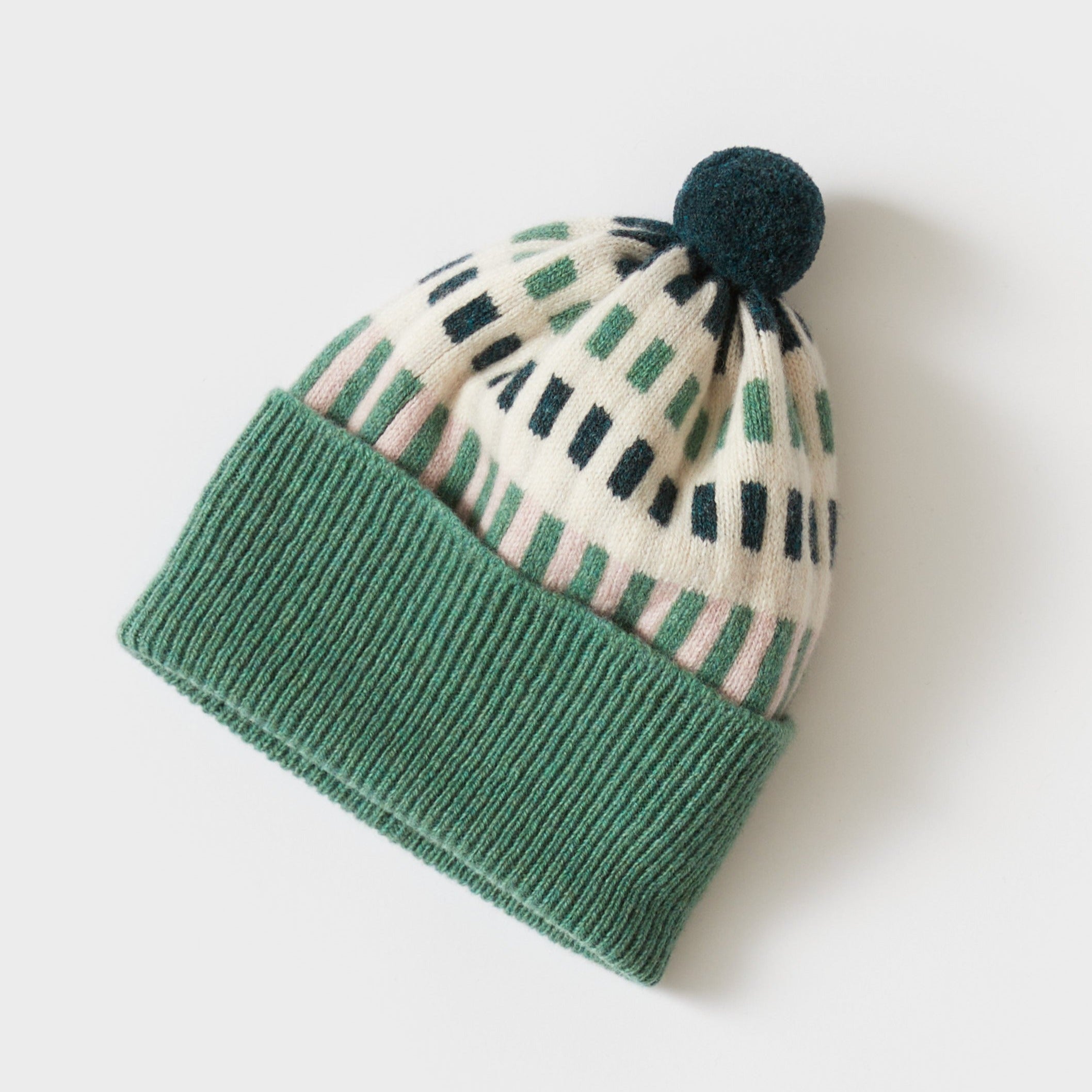 Green and cream knitted beanie with a dark green pompom.  The cream section features a geometric pattern.
