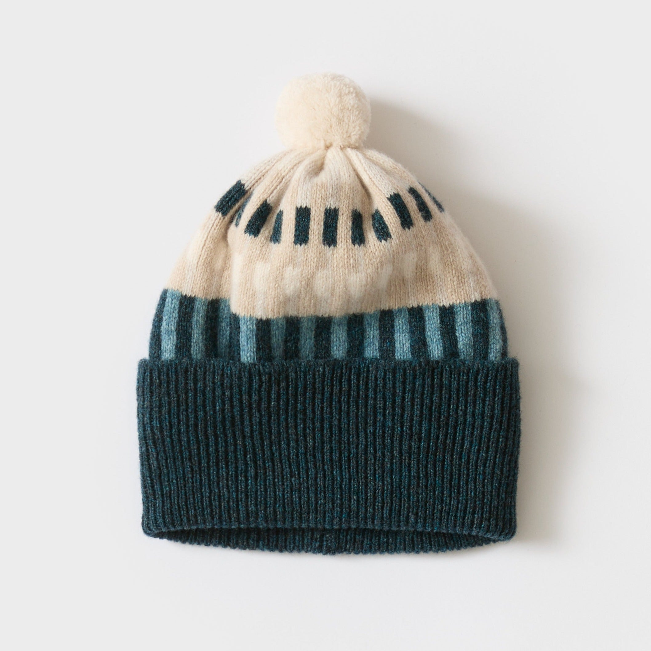 Knit beanie with off-white and teal stripes, teal cuff, and cream pompom.