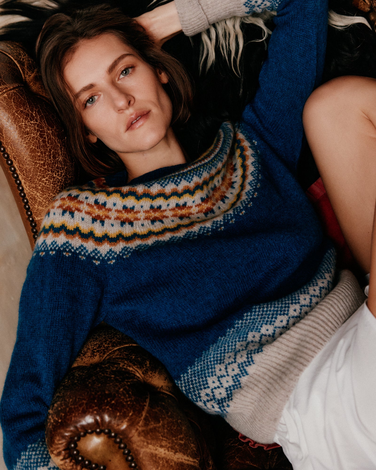 Woman wearing a patterned sweater lying on a couch