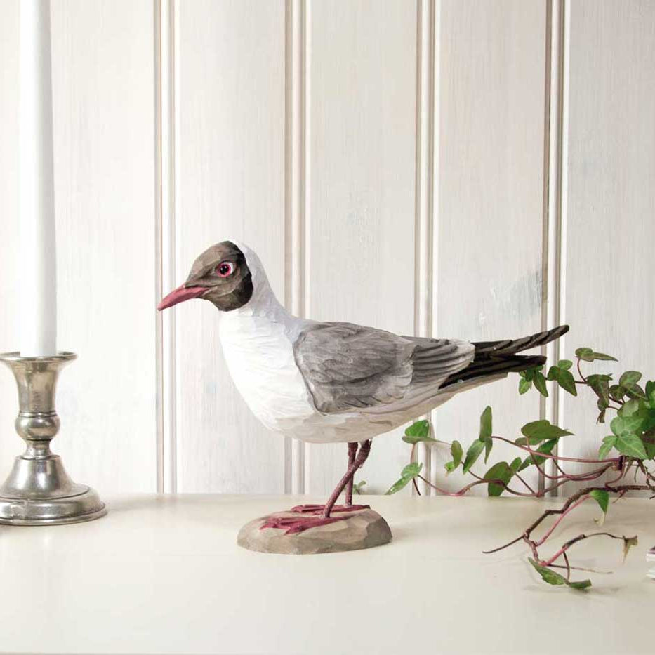Decorative bird on a pedestal with a candle and plant in the background