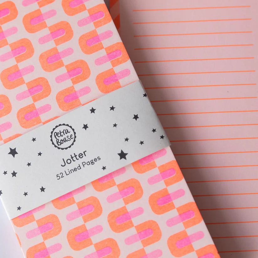 Notebook with geometric pattern and 'Petit&Famille' branding on a pink lined paper background.