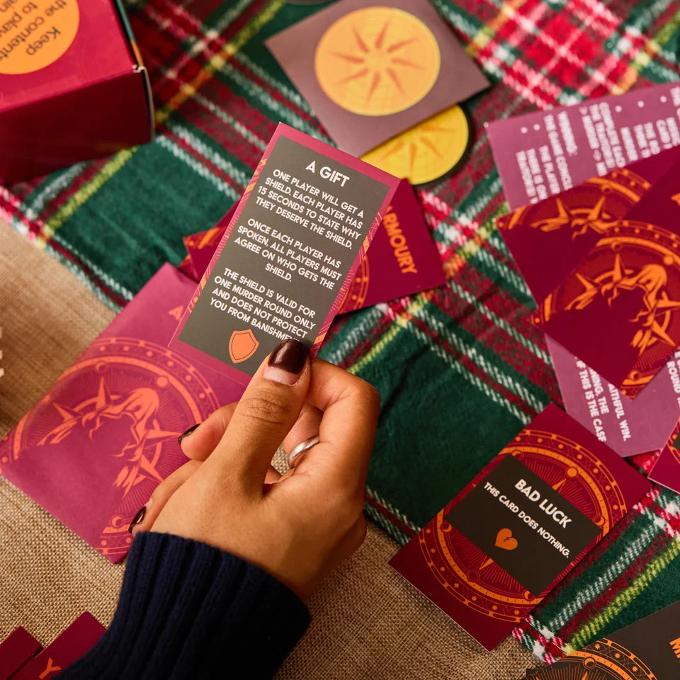 A hand holds a tarot card from a 'Love at First Sight' deck over a green and red plaid blanket, surrounded by other cards and boxes of the deck.
