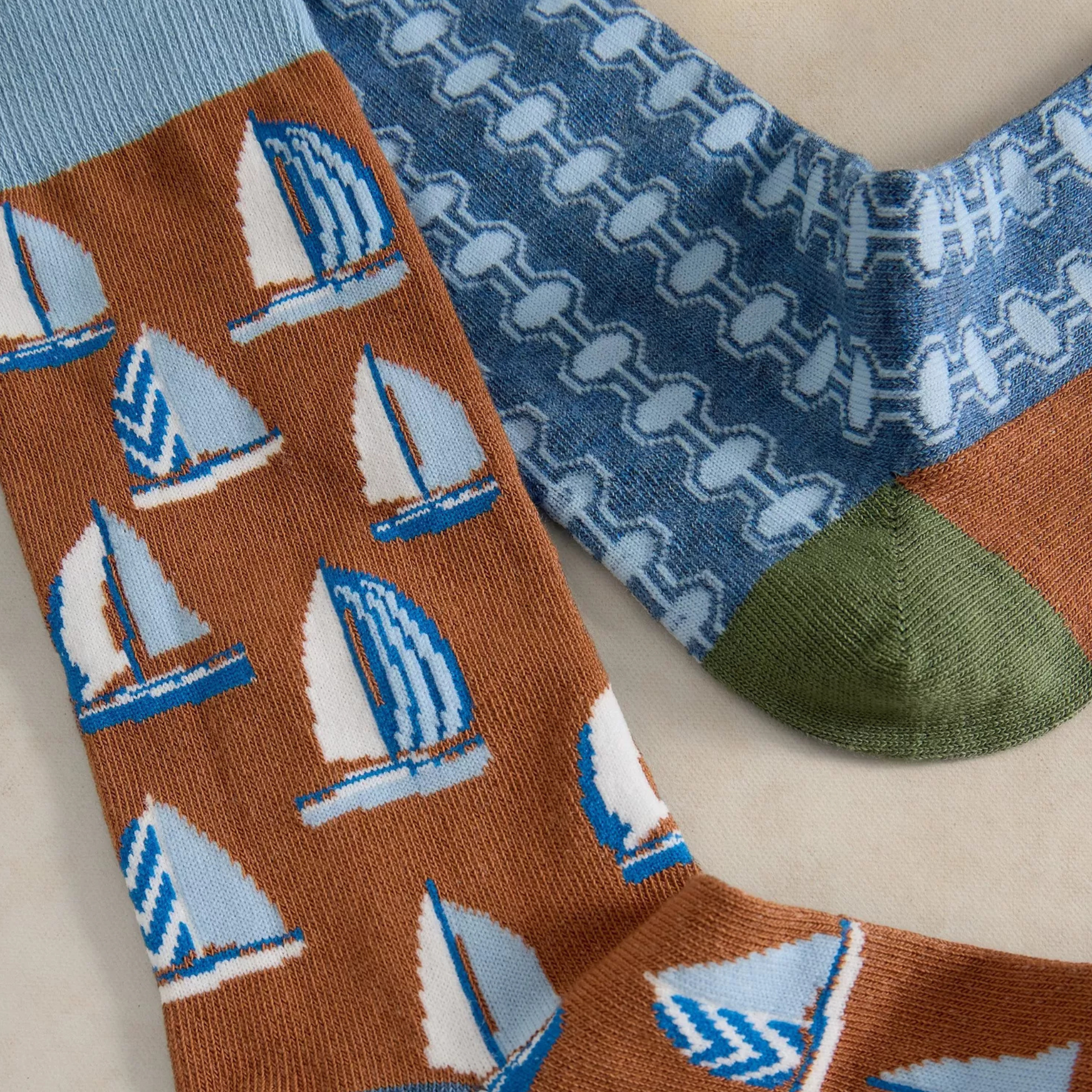 Two pairs of socks with sailboat pattern on a beige surface