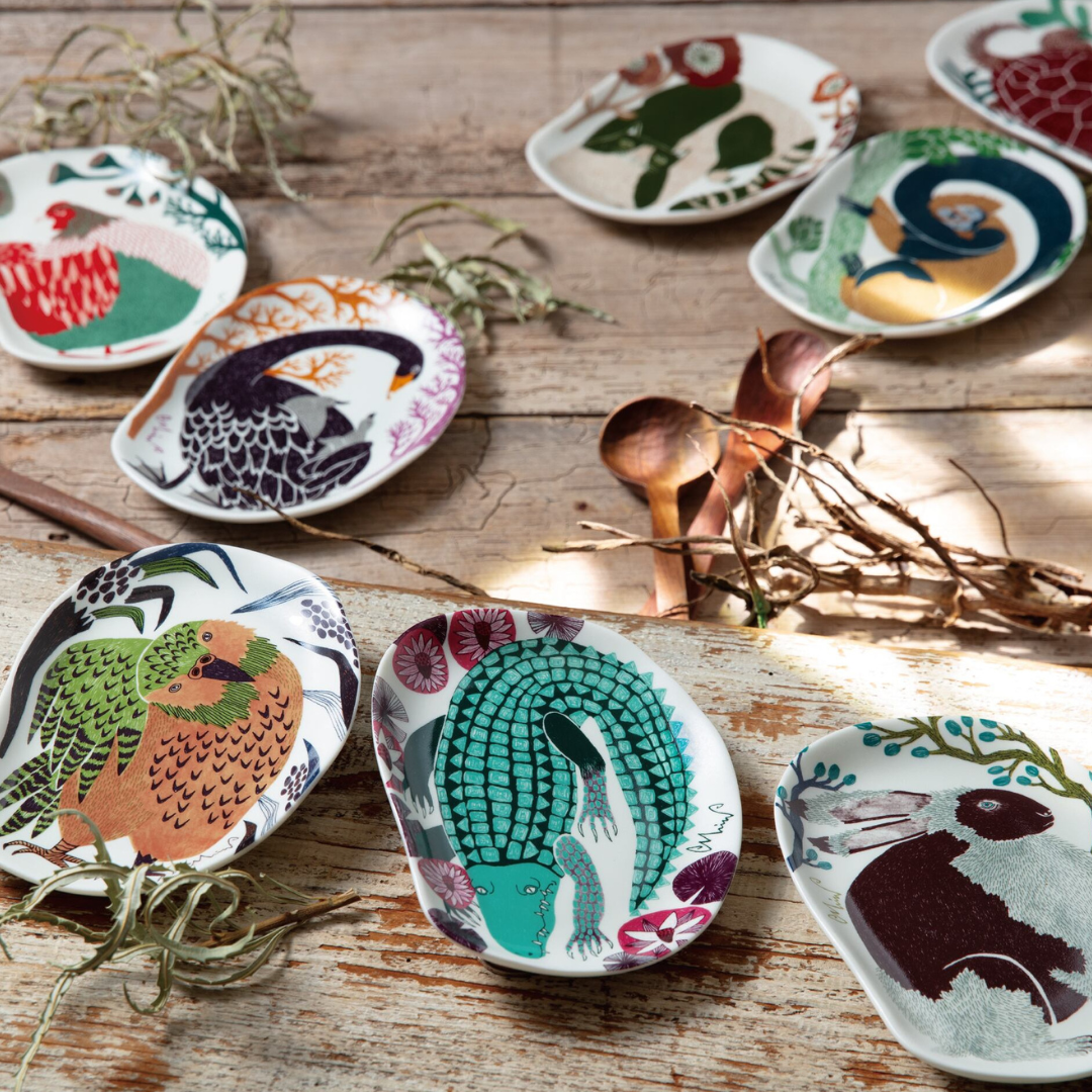 Set of small decorative plates with animal illustrations on a wooden surface.