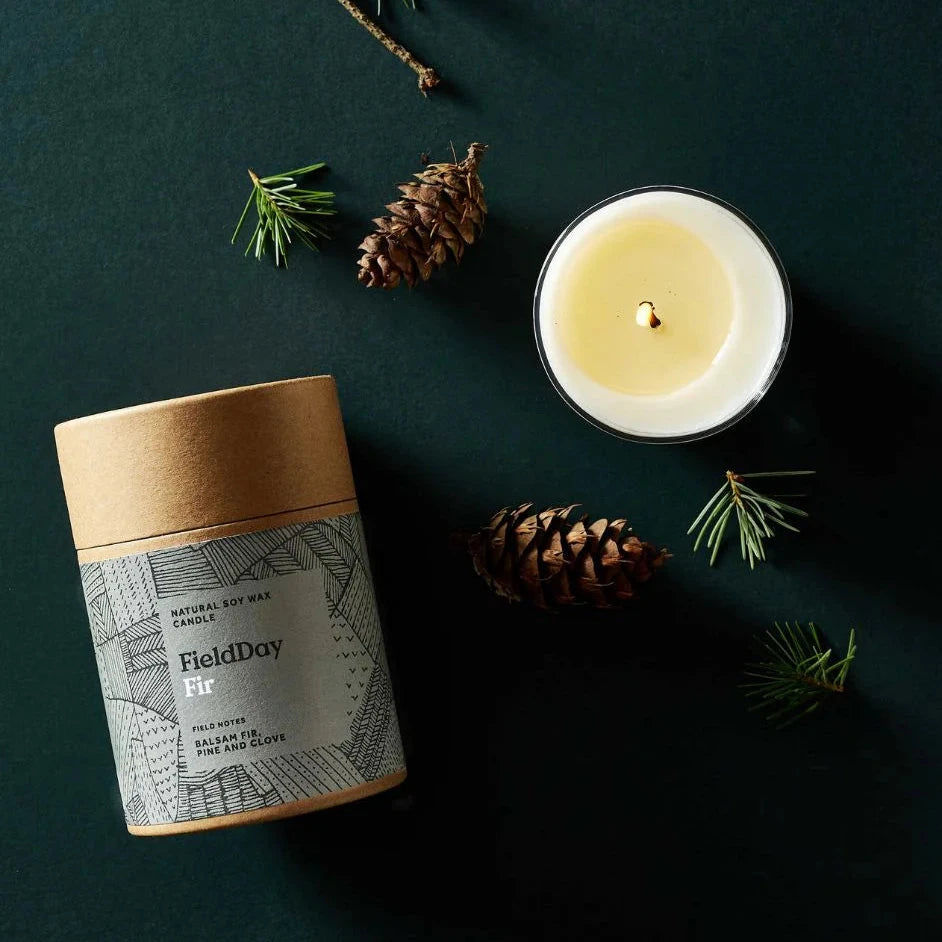 FieldDay Fir natural soy wax candle in a kraft tube with a geometric design.  A lit candle is also shown.