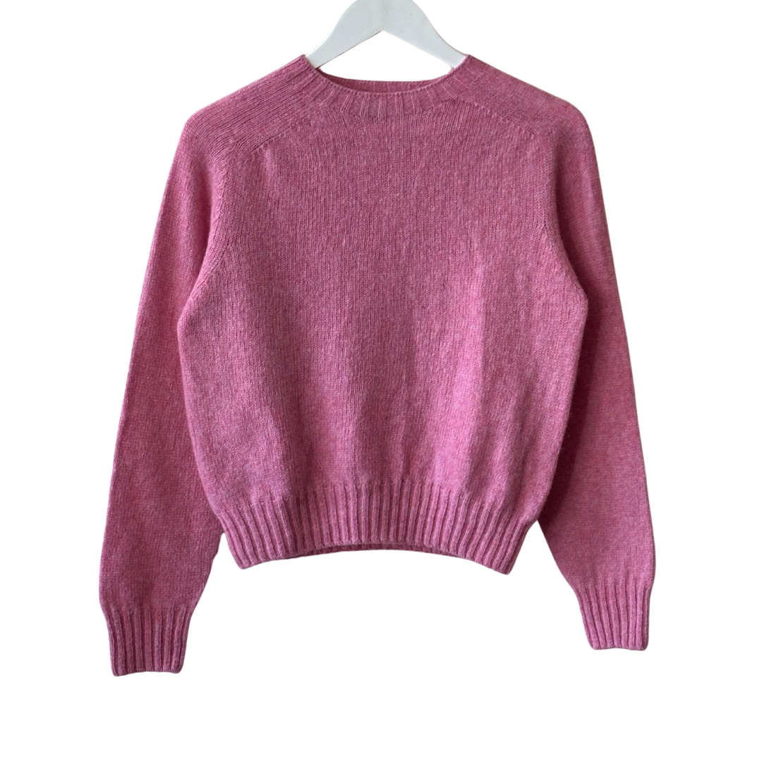 Pink crewneck wool sweater with long sleeves and ribbed cuffs and hem.