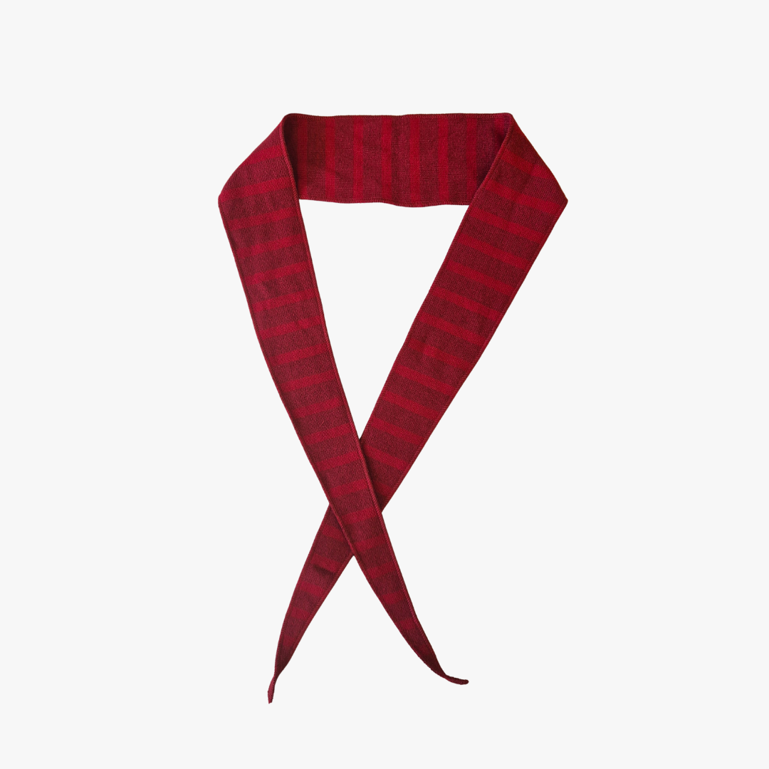 A dark red and black striped knit scarf, folded and tied in a loop against a plain white background.